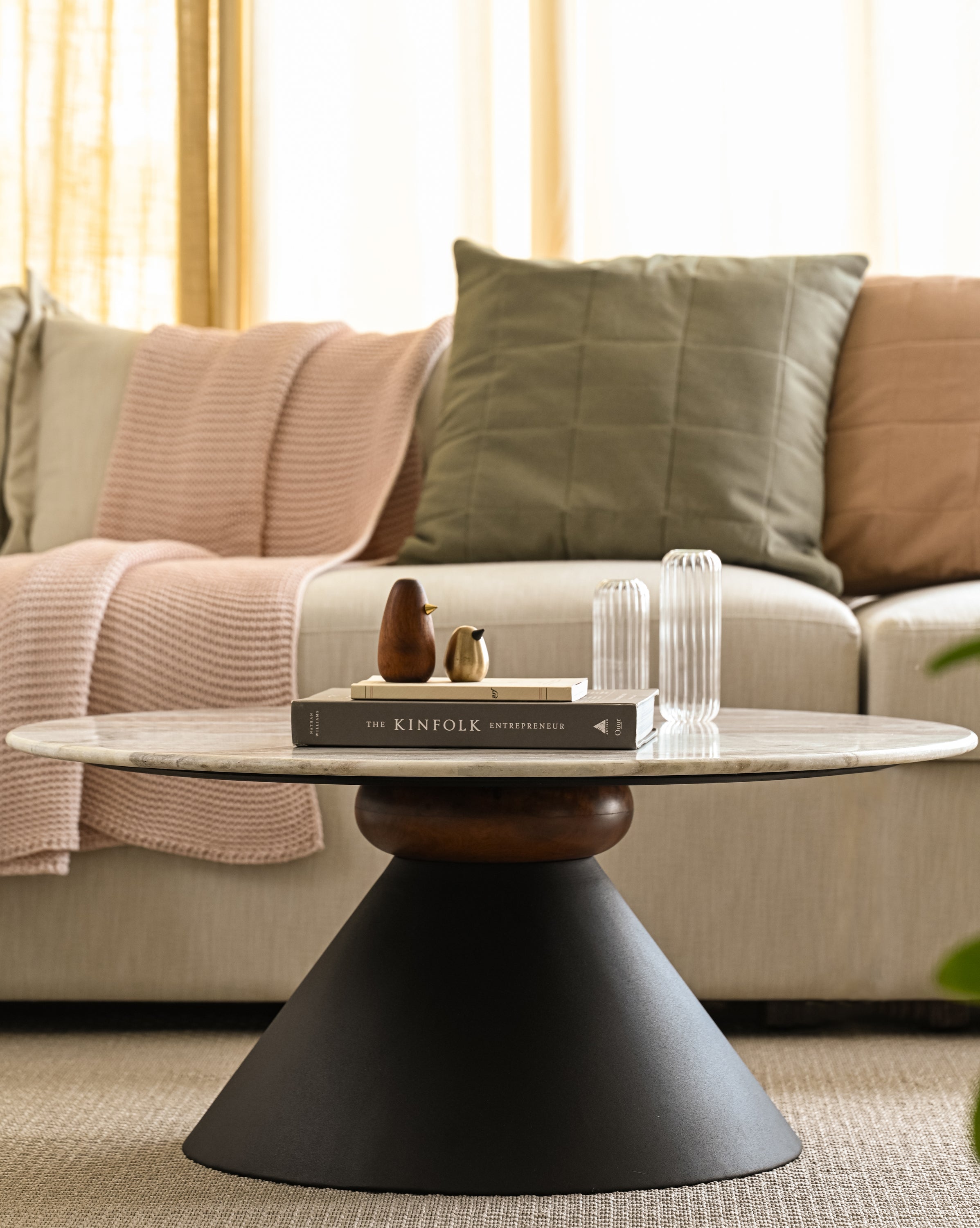 Marble coffee table with unique black pedestal base, decorated with Kinfolk book and vases.