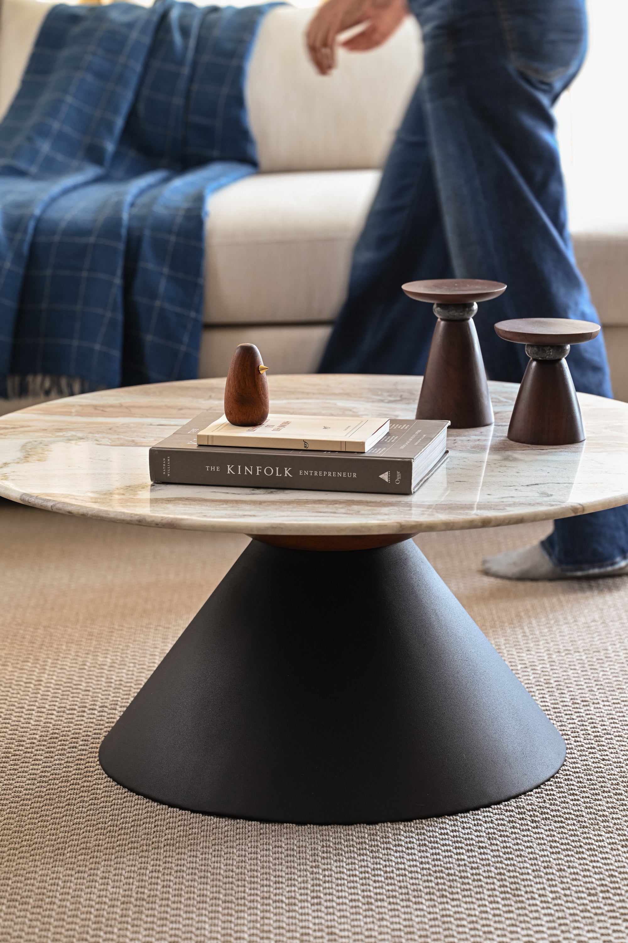 Contemporary round marble coffee table with black base in stylish living room interior.