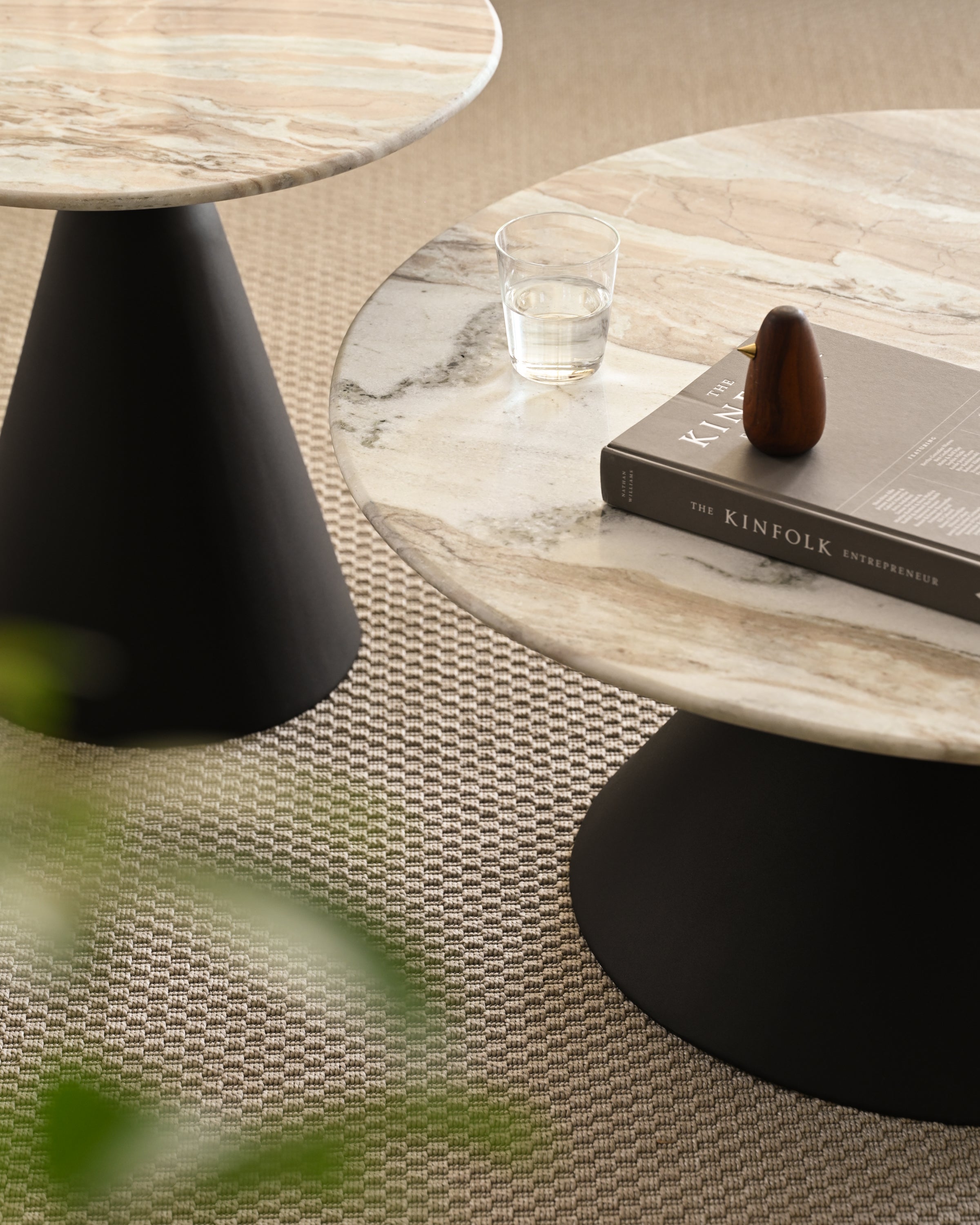 Close up of coffee and side tables with polished marble tops and bold black pedestal bases.