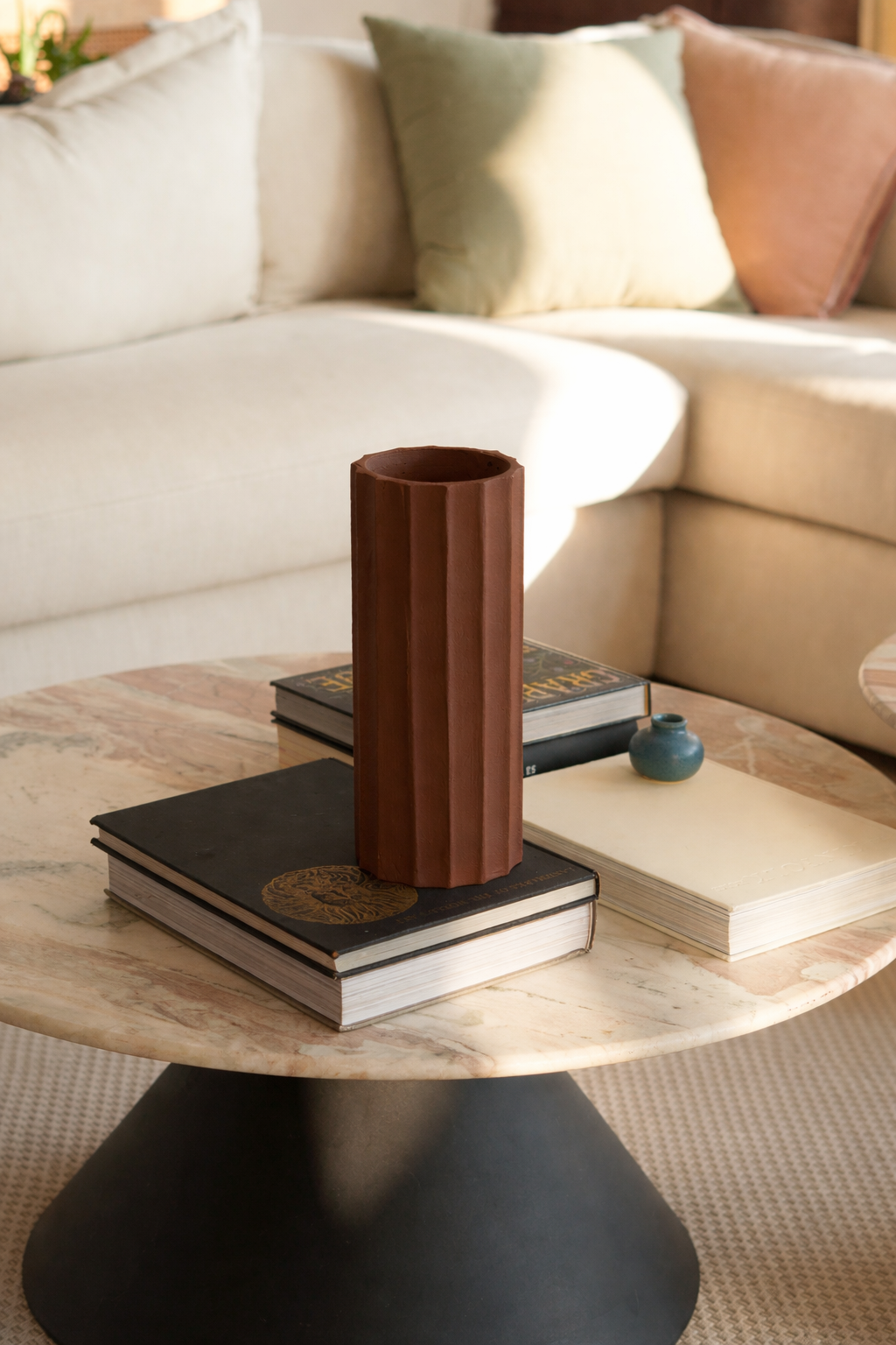 Decorative vase on a coffee table with books and a couch in the background