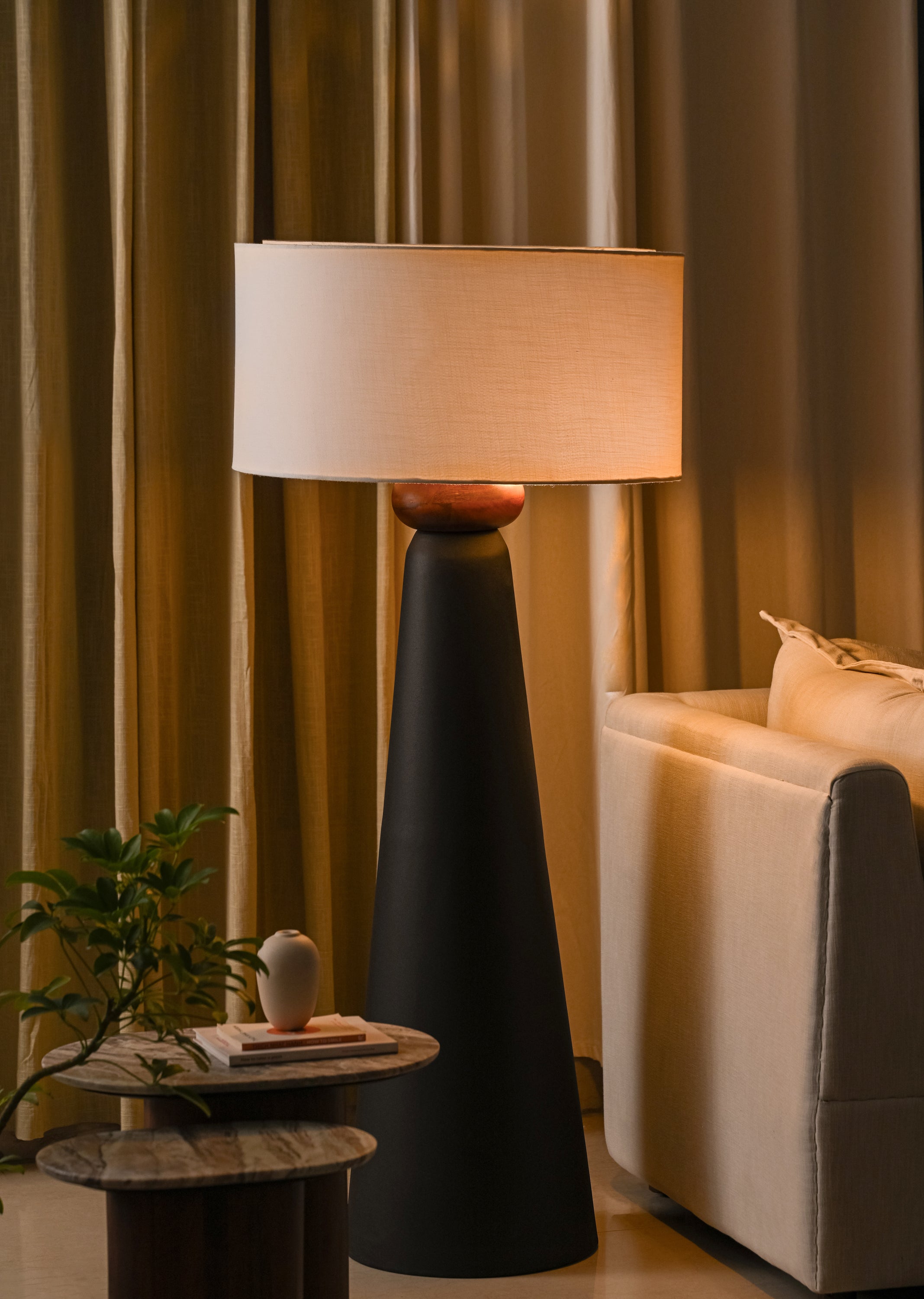 Decorative floor lamp in a living room setting with curtains and a sofa.