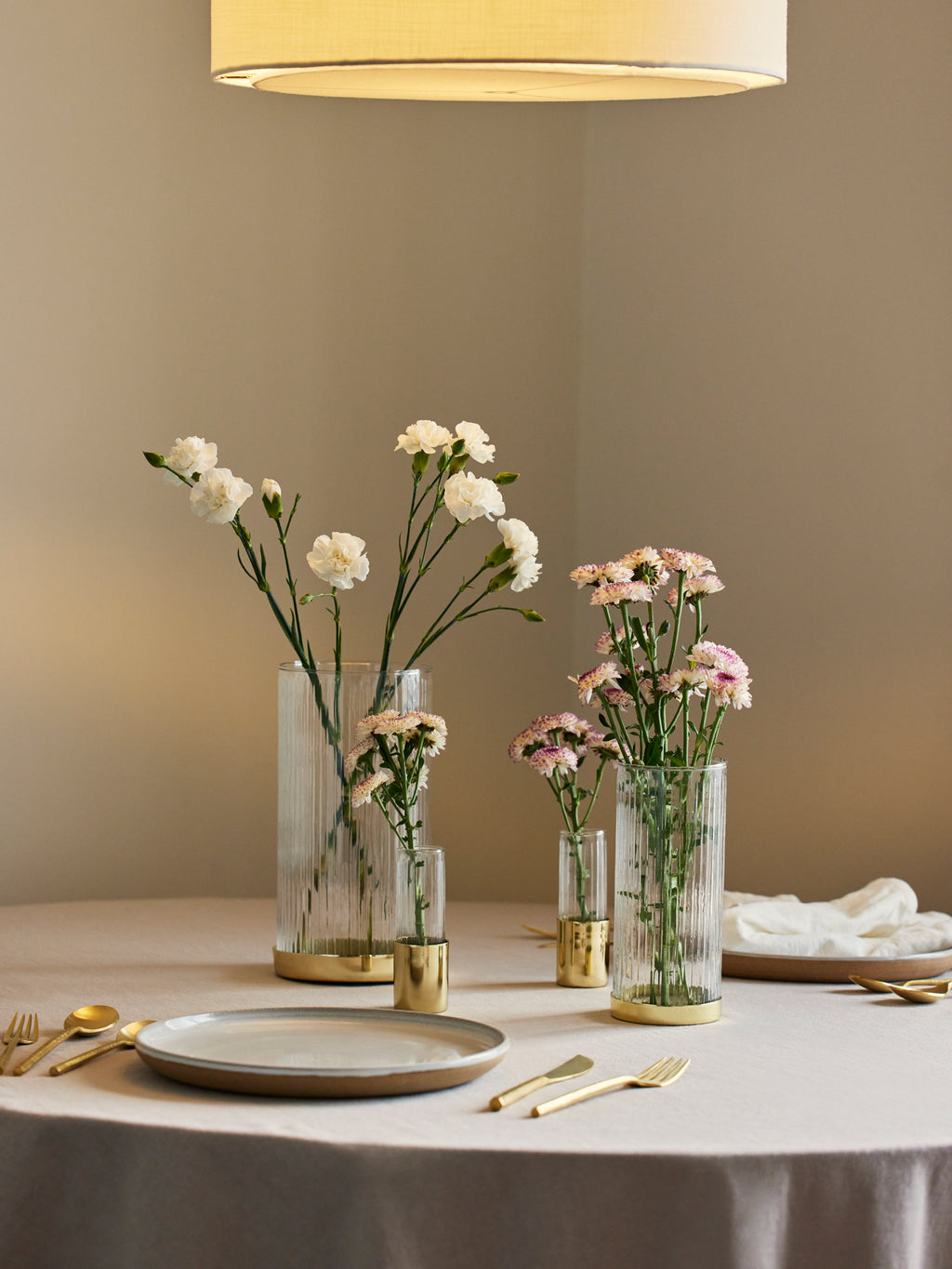 Table setting with fluted vases set with pink and white flowers.