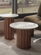 Two round marble top tables with wooden cylindrical bases in a room setting.