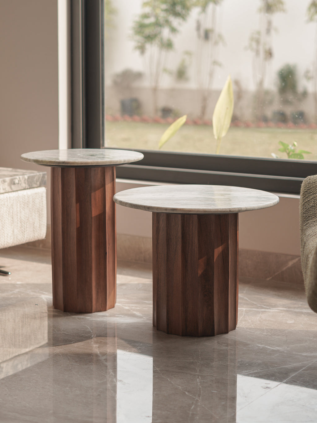 Two marble-top side tables with wooden bases in a modern interior setting.