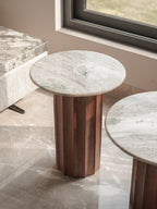 Round marble table with wooden base on a tiled floor