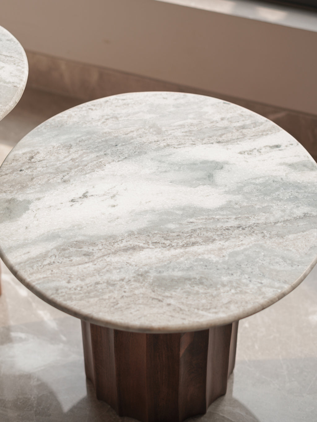 Round marble table with wooden base on a reflective surface