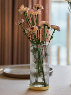 Clear glass vase for decor with gold plate with flowers in it.