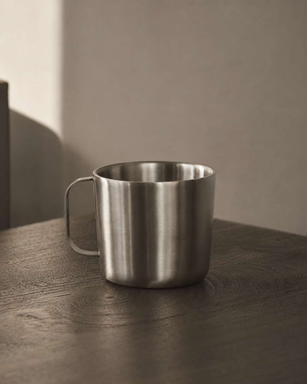 Stainless steel mug on a wooden surface with a neutral background