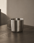 Stainless steel mug on a wooden surface with a neutral background