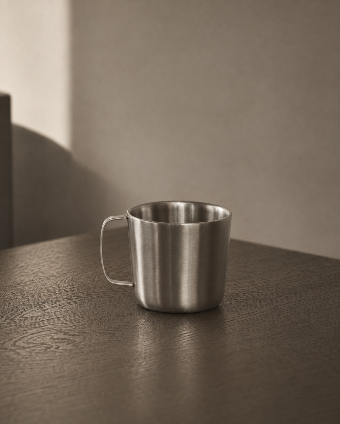 Steel double wall mug on a wooden surface with a neutral background