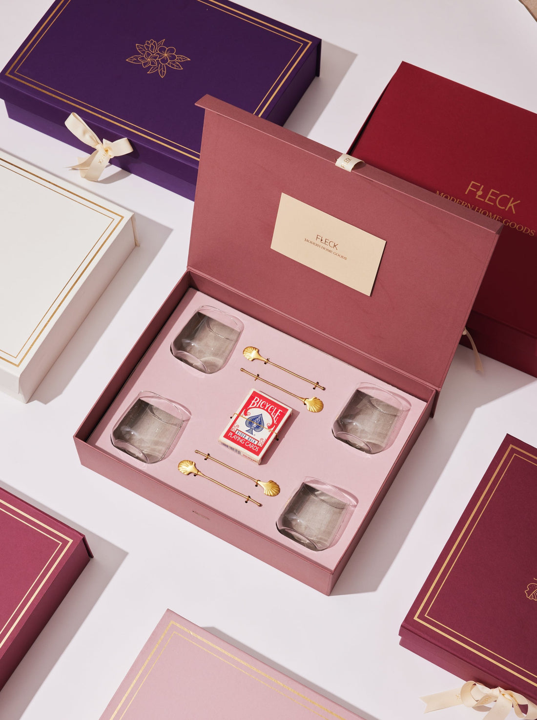 Gift Boxes with dusty pink open with cards, glasses and drink stirrers