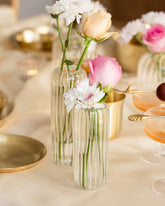 Clear glass flower vase with pink roses, placed on a white tablecloth. 