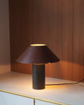 Modern table lamp made with leather with a brown shade on a marble surface with wooden panel background