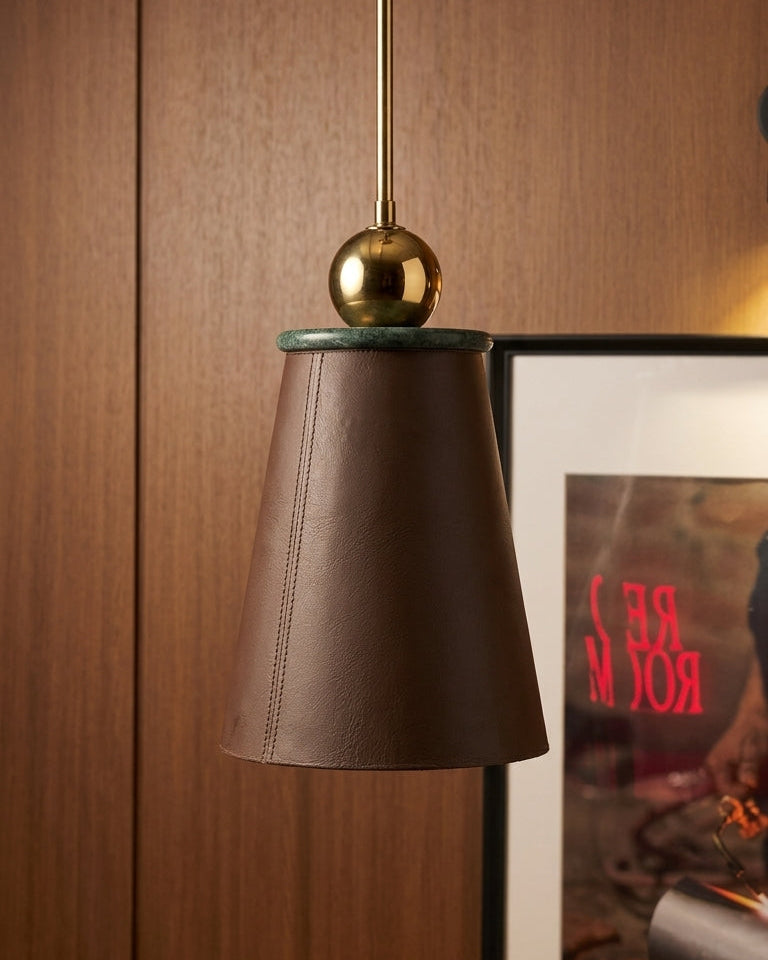 Brown pendant light with gold fixture against a wooden wall