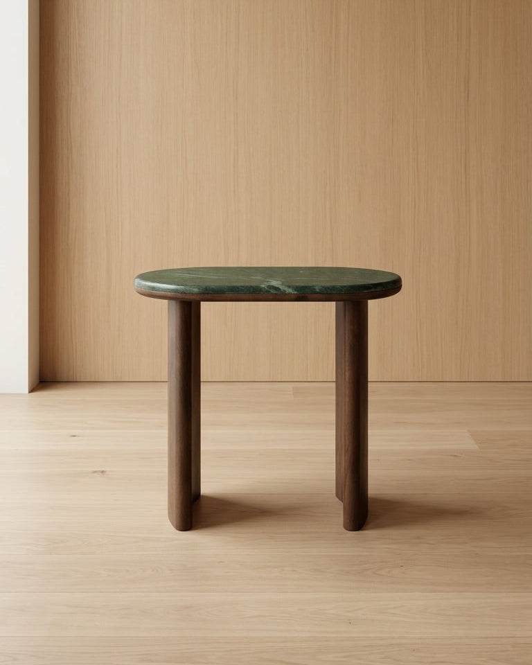 Small table with green marble top and wooden legs against a wooden wall.