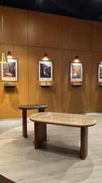 Wooden dining table and bench against a wooden wall with framed pictures.