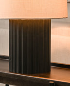 Table lamp with a black base and peach-colored shade on a wooden surface.
