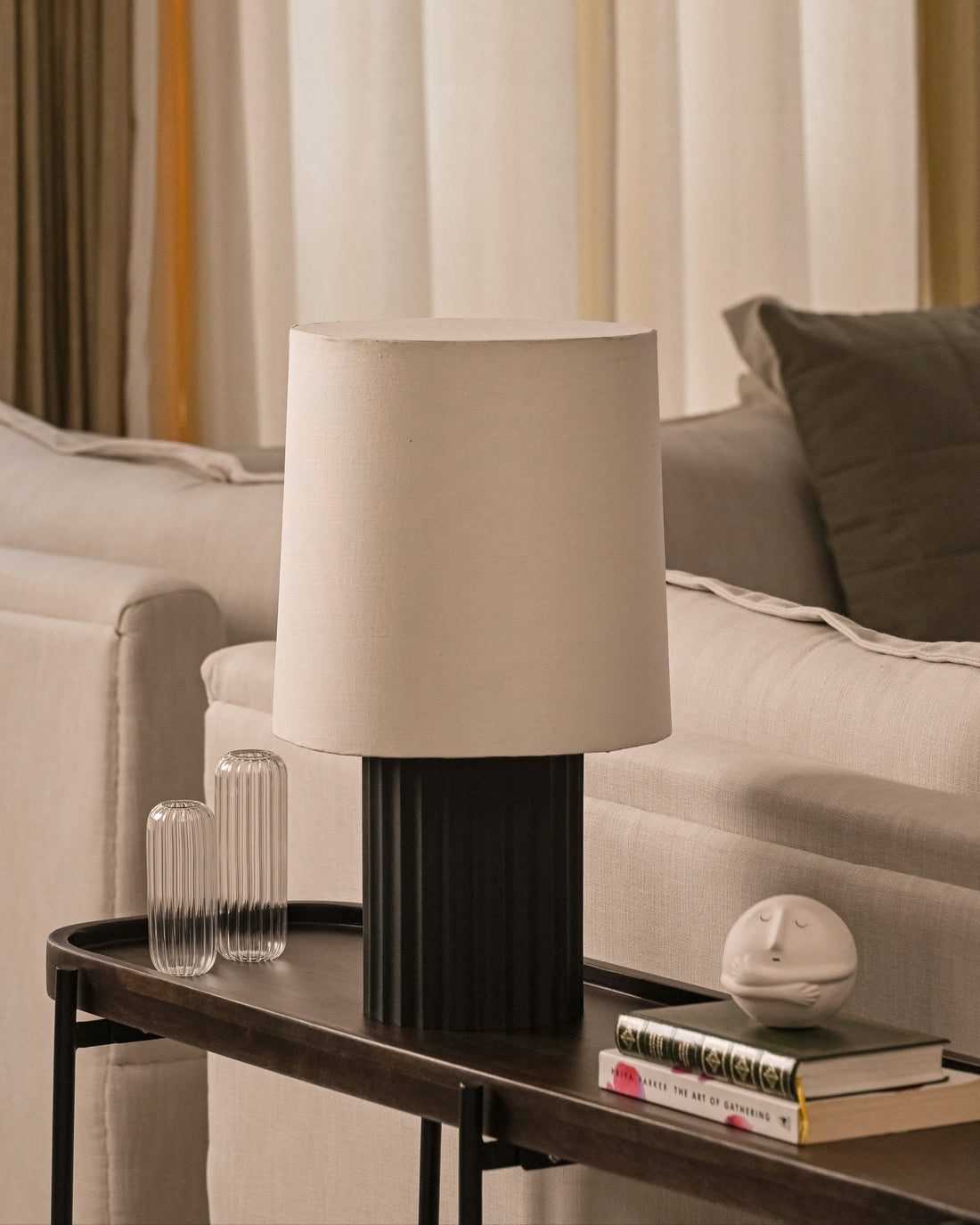 Black and Beige origami lamp on a table with a sofa and striped curtains in the background