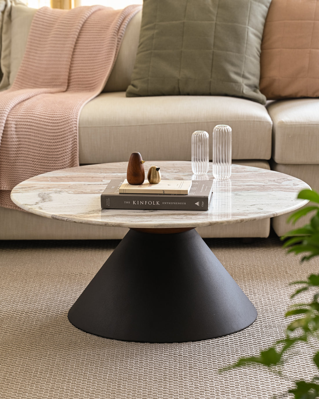 Minimalist marble coffee table with solid black base with books and decorative items.
