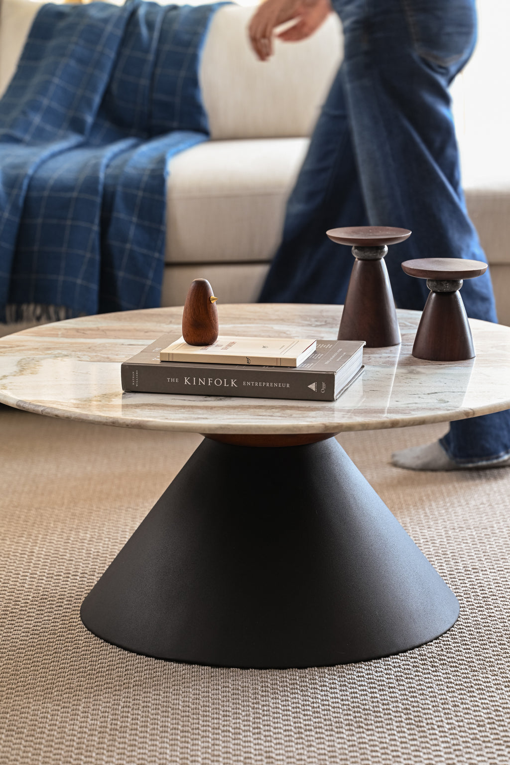 Contemporary round marble coffee table with black base in stylish living room interior.