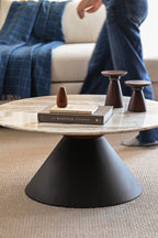 Contemporary round marble coffee table with black base in stylish living room interior.