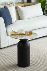 Cozy living room setting with a modern side table holding a book and glass beside a neutral-toned sofa.