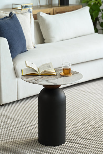 Cozy living room setting with a modern side table holding a book and glass beside a neutral-toned sofa.