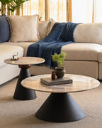 Accent table and coffee table nested together with round marble top and matte black pedestal in cozy living space.