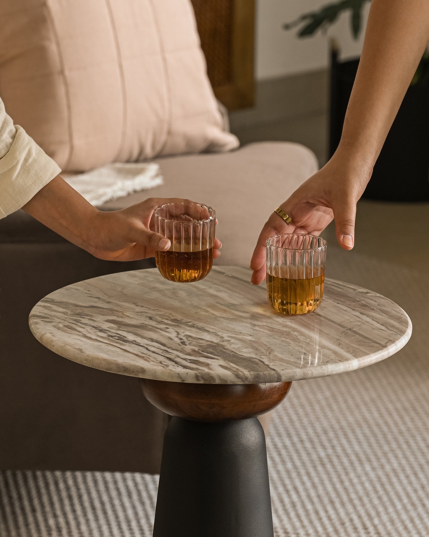 Close-up of modern marble drinks table with black base and glasses being picked up.