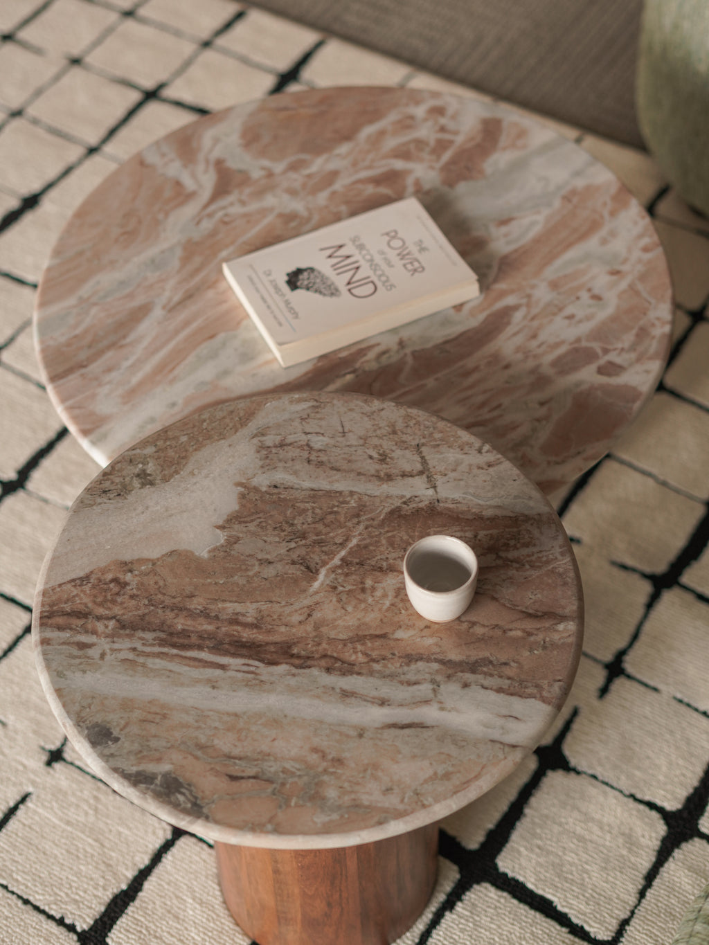 Round marble coffee table with a book and a cup on a patterned rug