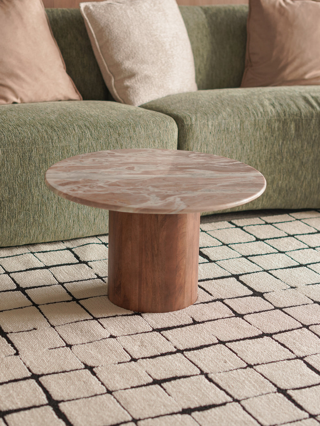 premium marble and wood coffee table in front of a green sofa on a patterned rug
