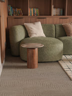 Green sofa with wooden side table and books on shelves in a room.