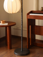 Floor lamp with fabric white shade and black stand.
