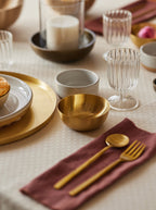 Small Heirloom brass bowl in setting with brass cutlery and fluted stemware