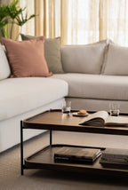 Modern living space featuring a two-tier coffee table with curated books, drinkware, and cozy neutral sofa.