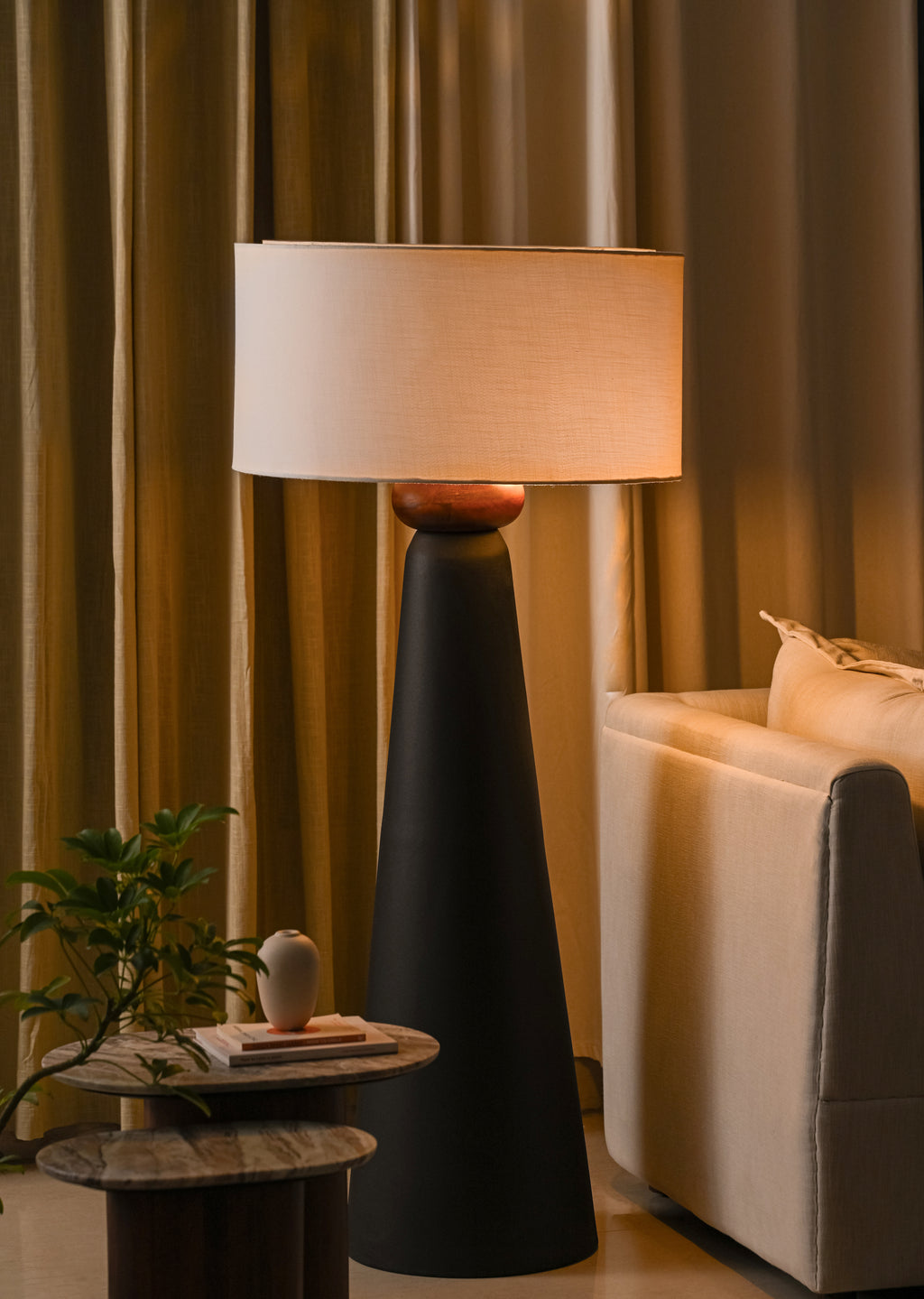 Decorative floor lamp in a living room setting with curtains and a sofa.
