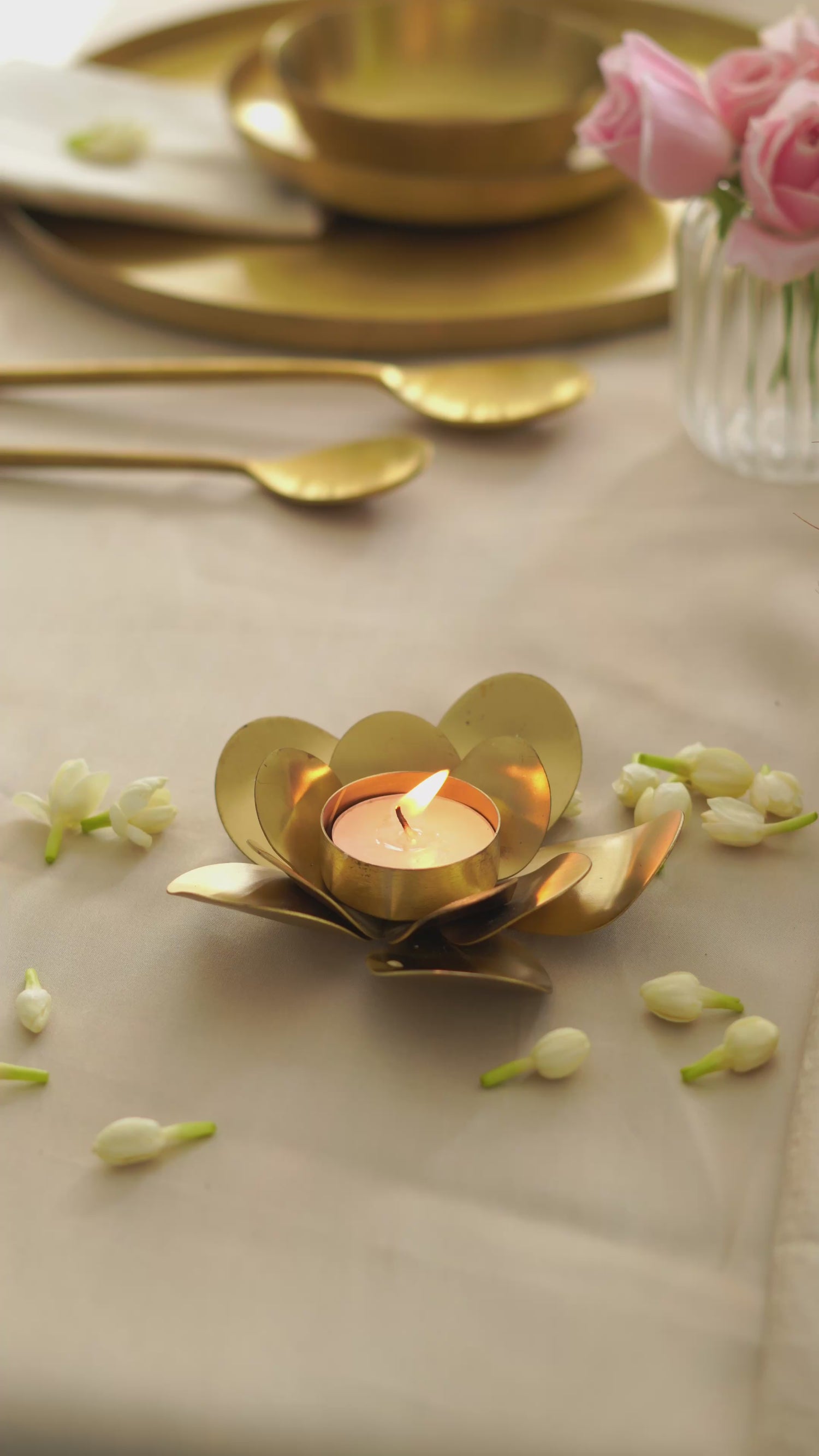Brass lotus tealight holder glowing warmly with a lit candle in a home setting.