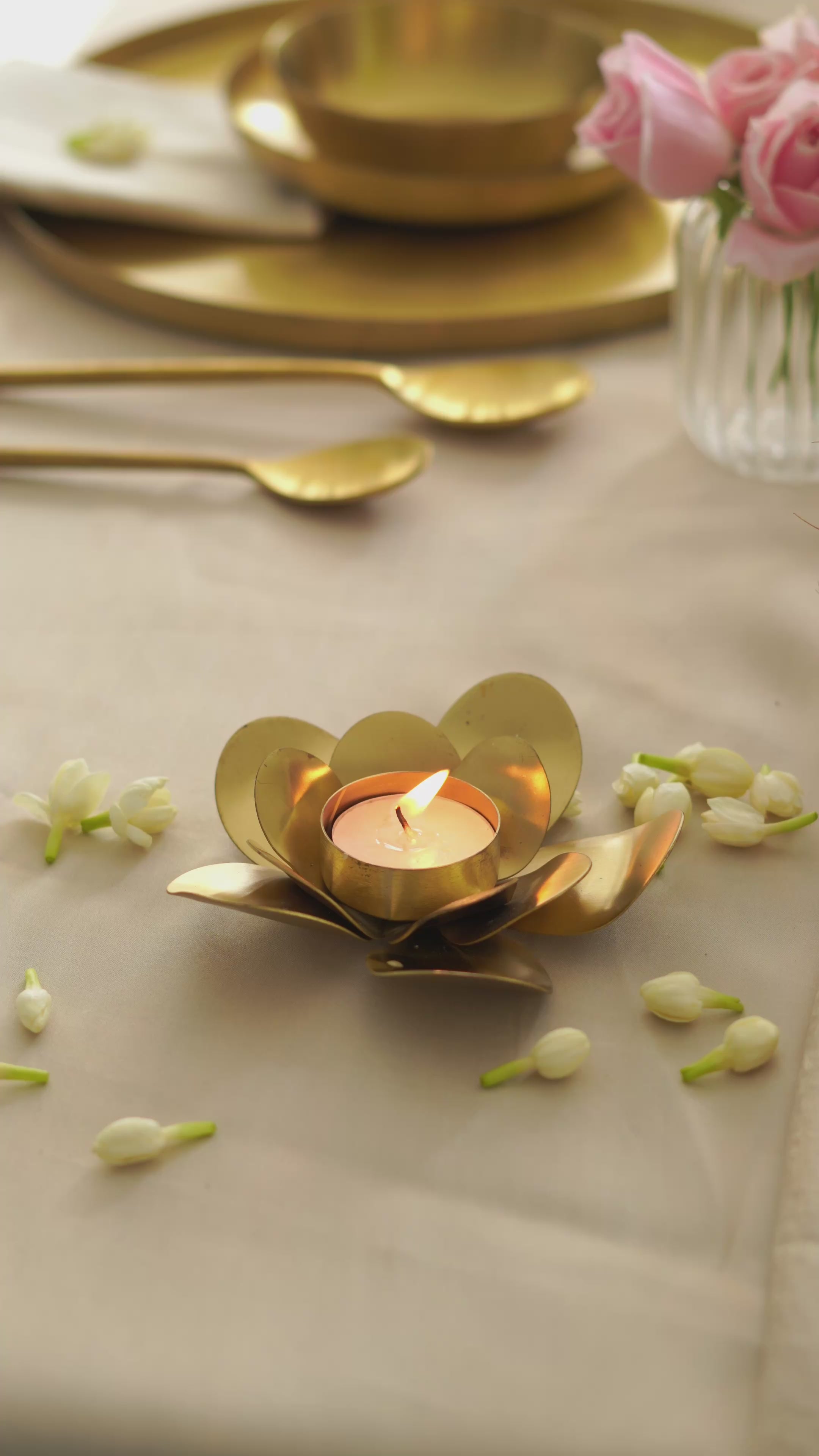 Brass lotus tealight holder glowing warmly with a lit candle in a home setting.