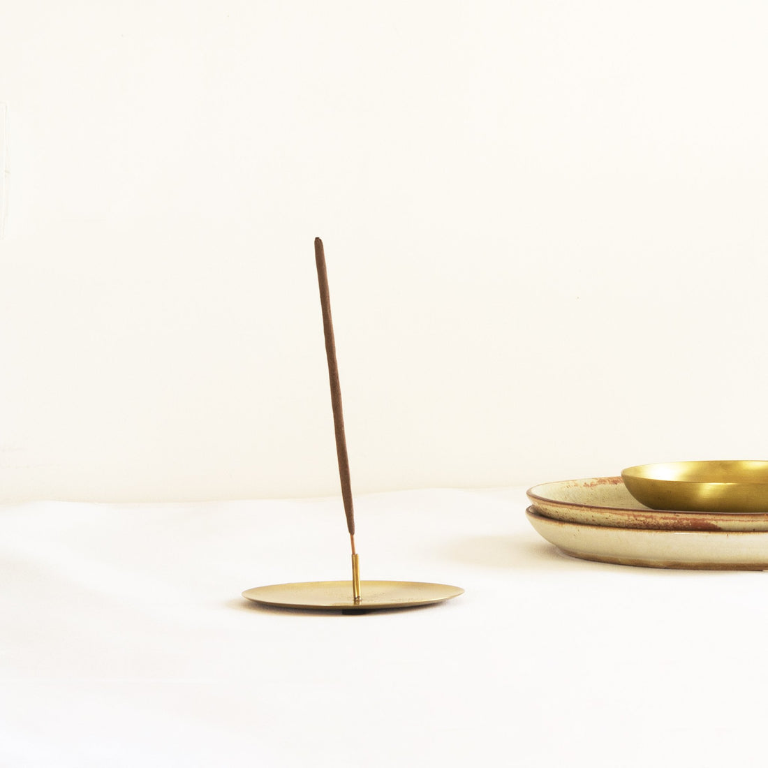 Brass Incense stick holder with two incense stick with ceramic plates in the background. Part of heirloom collection by Fleck India